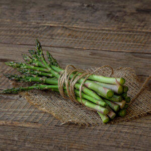 Bunched asparagus with string wrapped around on a wooden table.